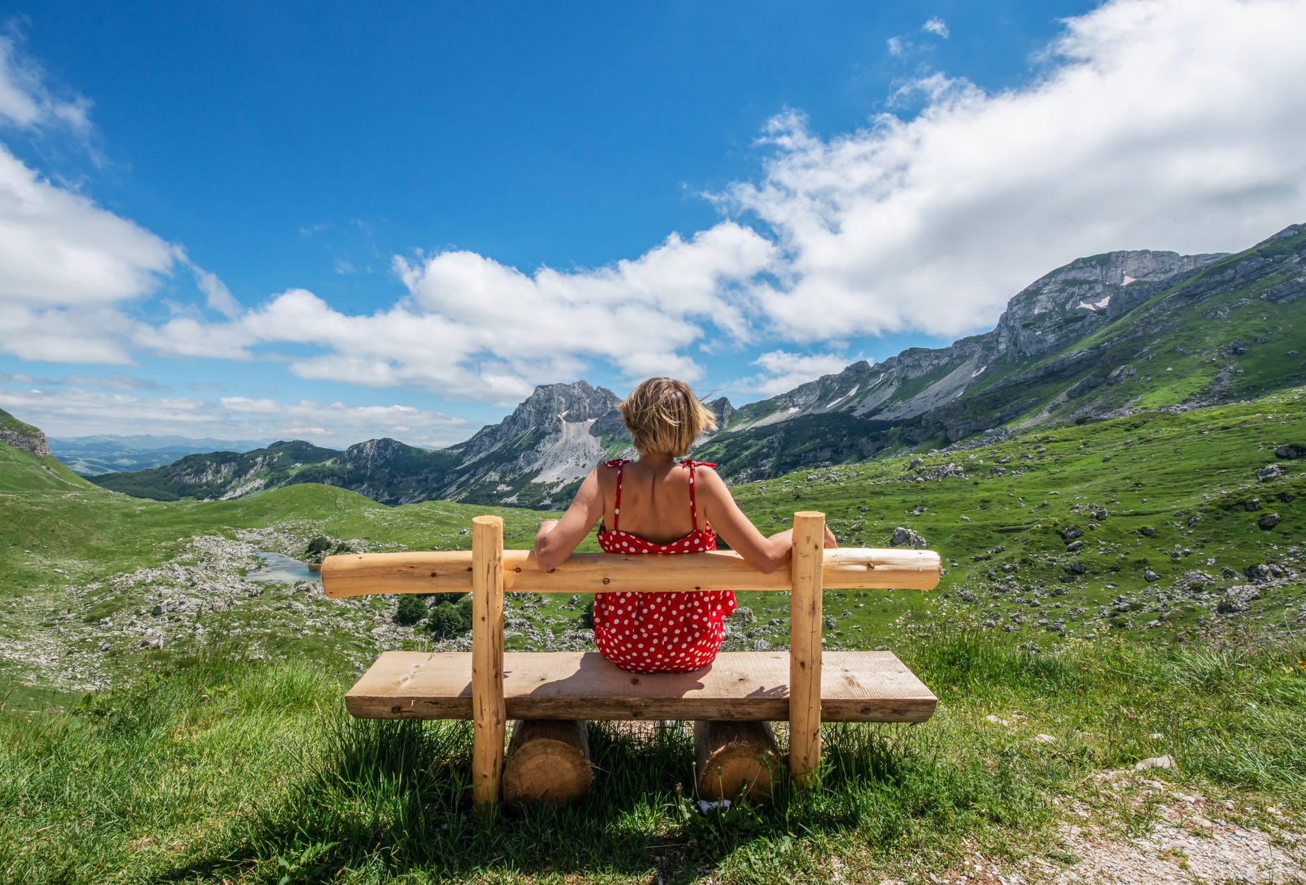 woman resting on wooden bench in meadow with fresh grass