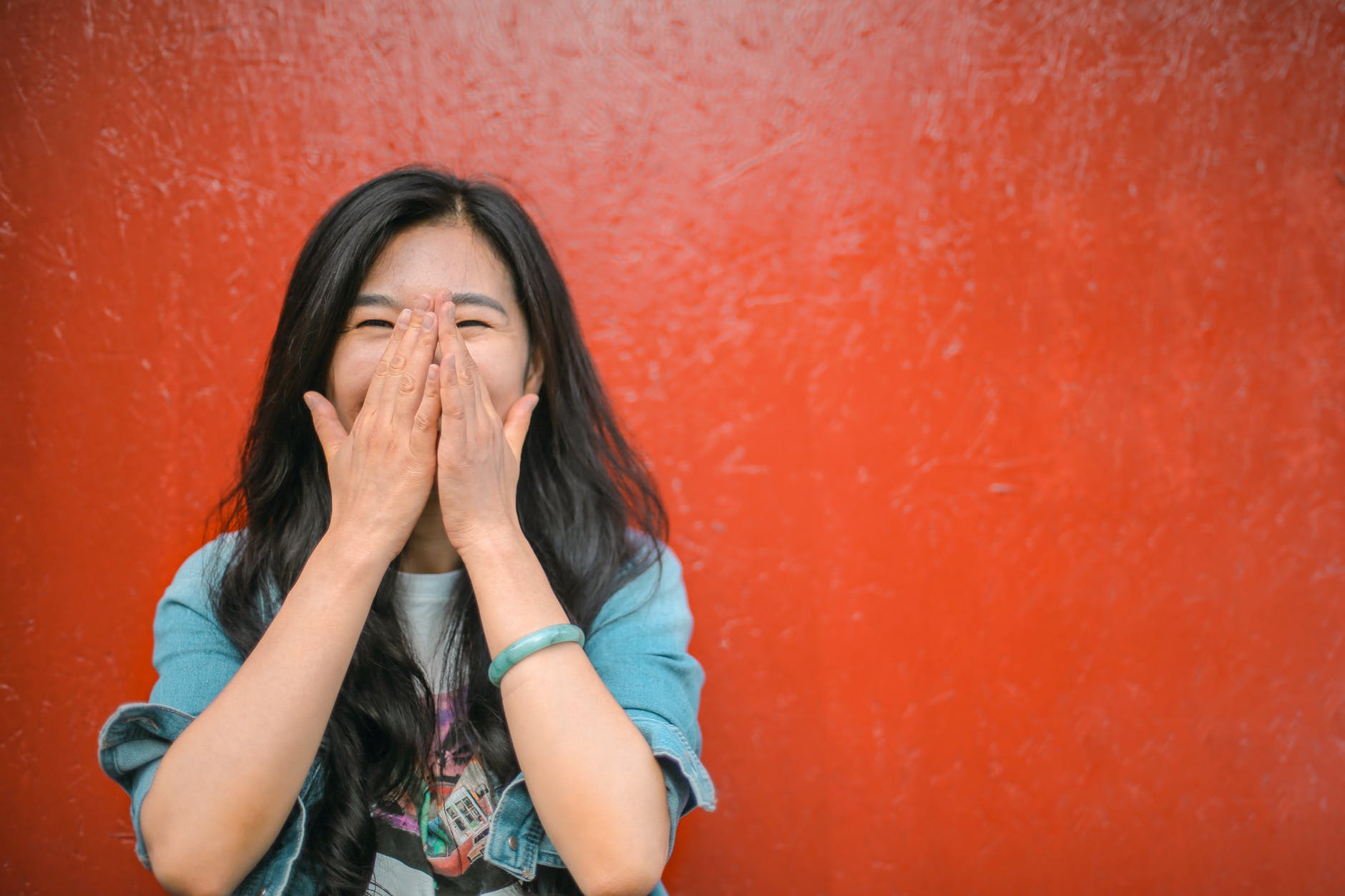 cheerful ethnic woman against vivid red painted wall